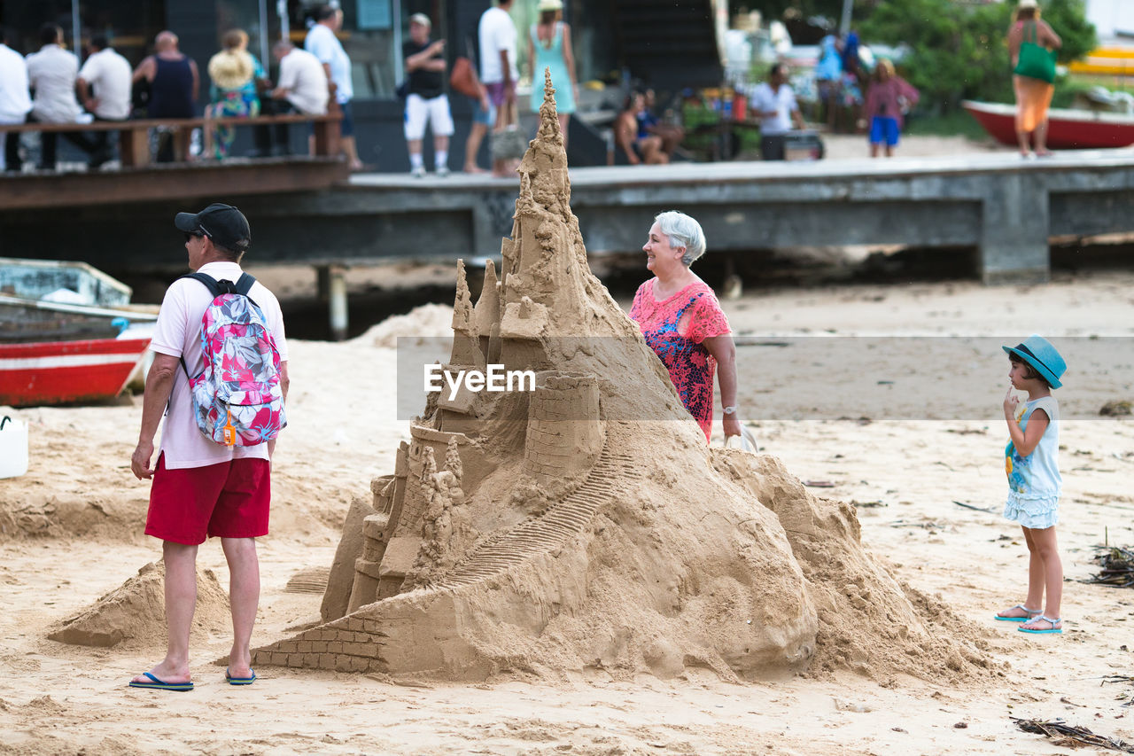 REAR VIEW OF PEOPLE WALKING ON BEACH