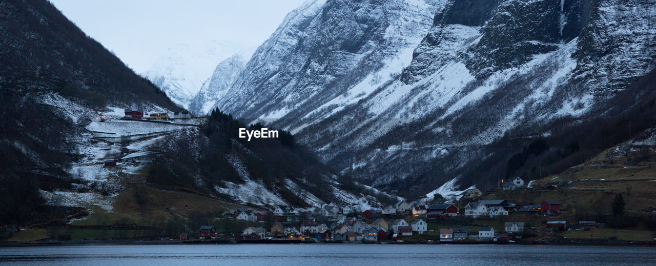 mountain, snow, mountain range, cold temperature, water, scenics - nature, winter, nature, beauty in nature, environment, architecture, landscape, lake, travel destinations, no people, sky, snowcapped mountain, land, building, built structure, travel, building exterior, outdoors, ice, glacial landform, city, tranquil scene, waterfront, tranquility, rock, day, tourism