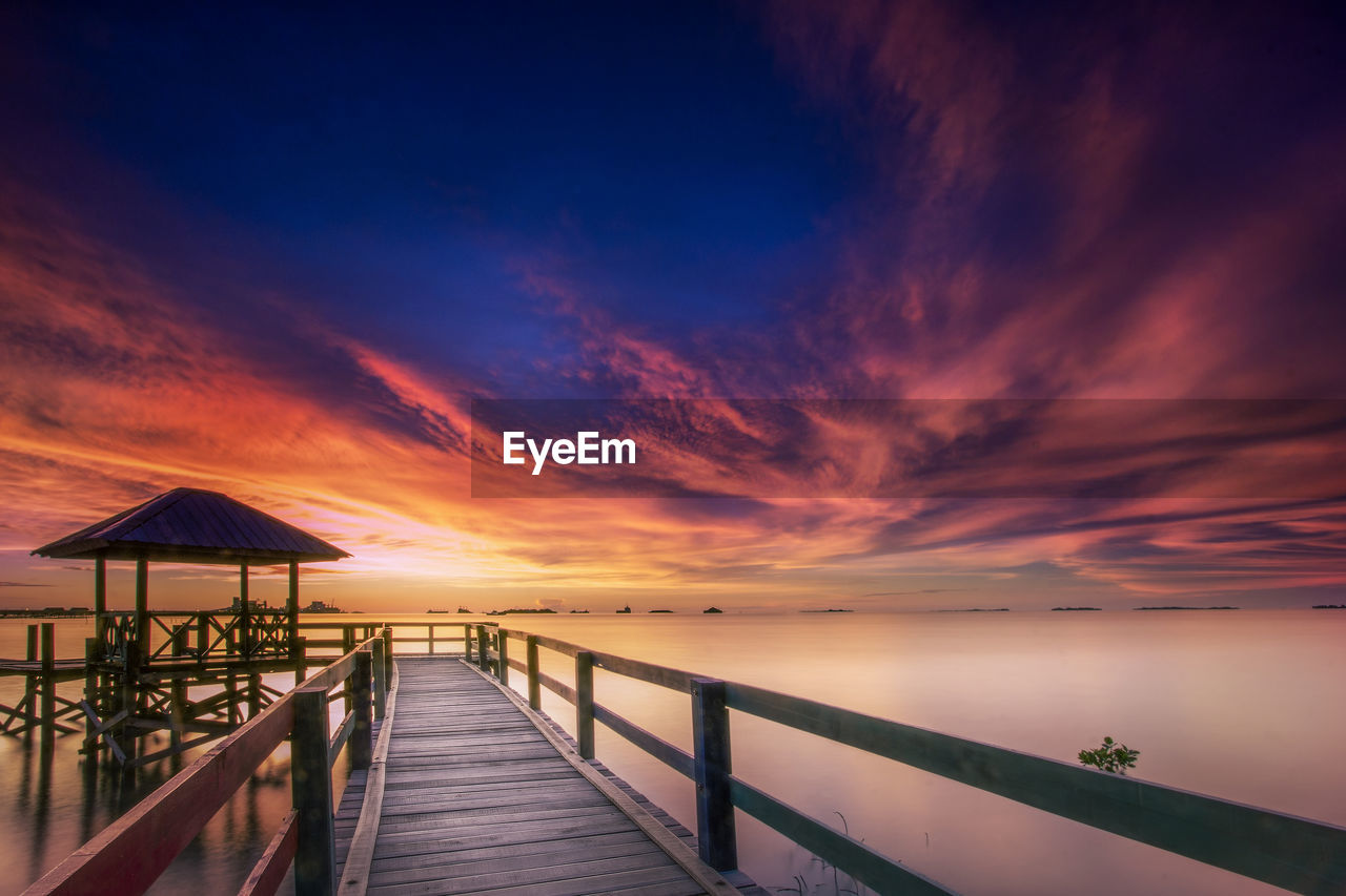 Pier over sea against sky during sunset