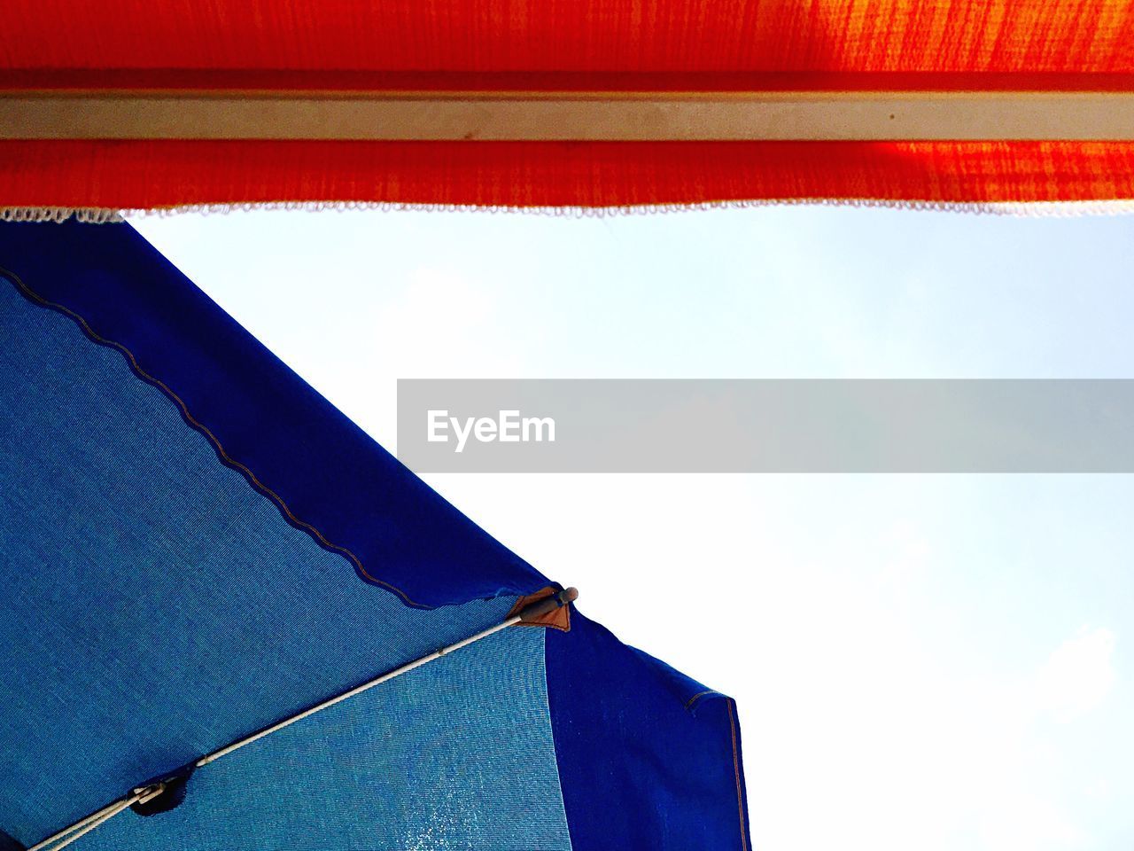 Low angle view of cropped umbrella against clear sky