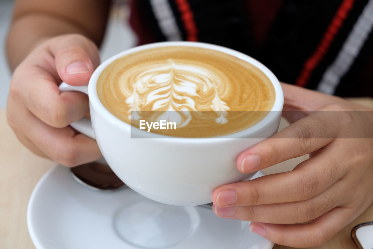 MIDSECTION OF WOMAN HOLDING CUP OF COFFEE