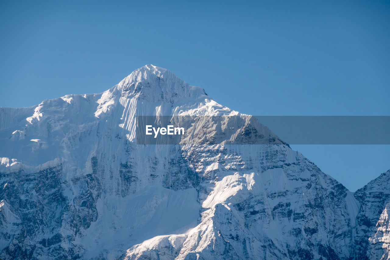 Aerial view of snowcapped mountain against clear blue sky