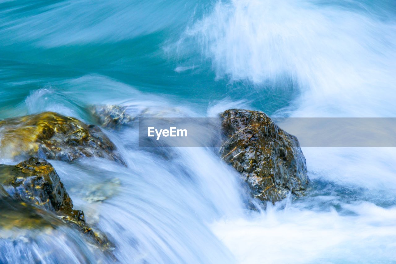 SCENIC VIEW OF WATER FLOWING THROUGH ROCKS