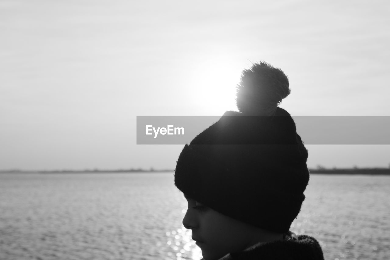 Rear view of boy wearing warm clothing against sea