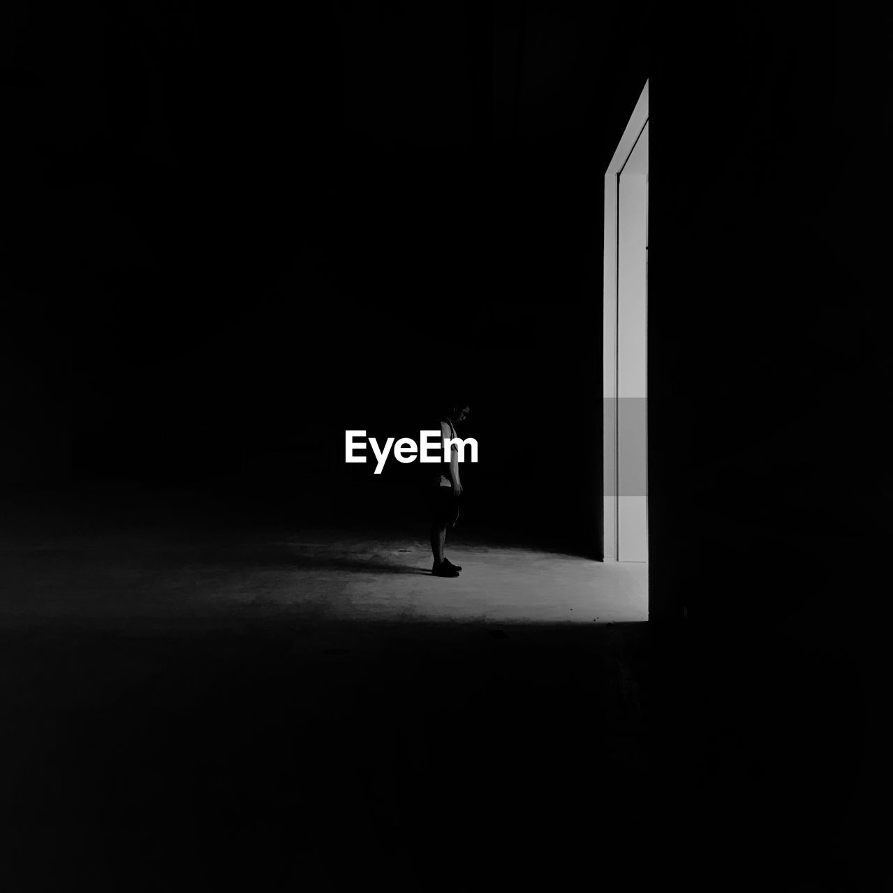 Side view of man standing by doorway in darkroom at night