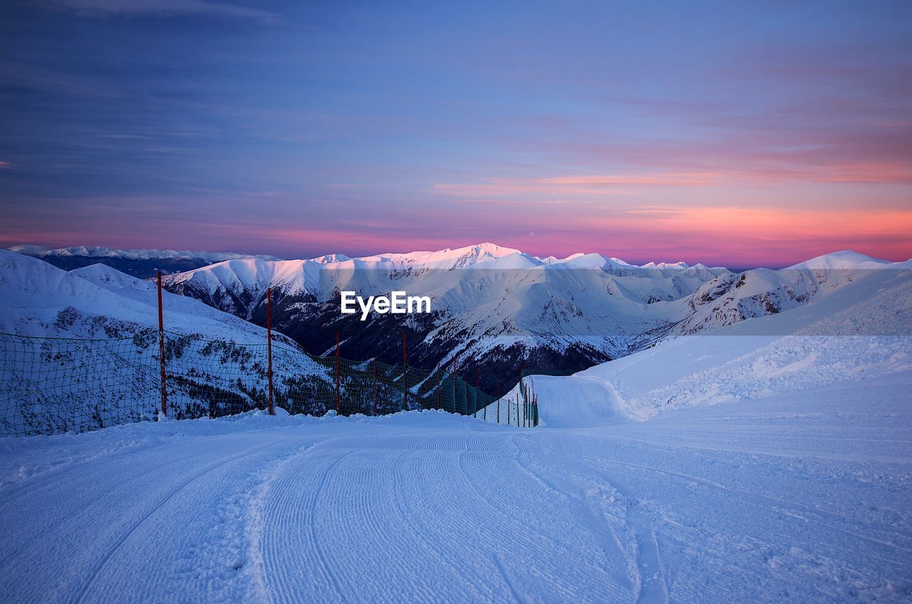 SCENIC VIEW OF SNOW COVERED MOUNTAIN AGAINST SKY DURING SUNSET