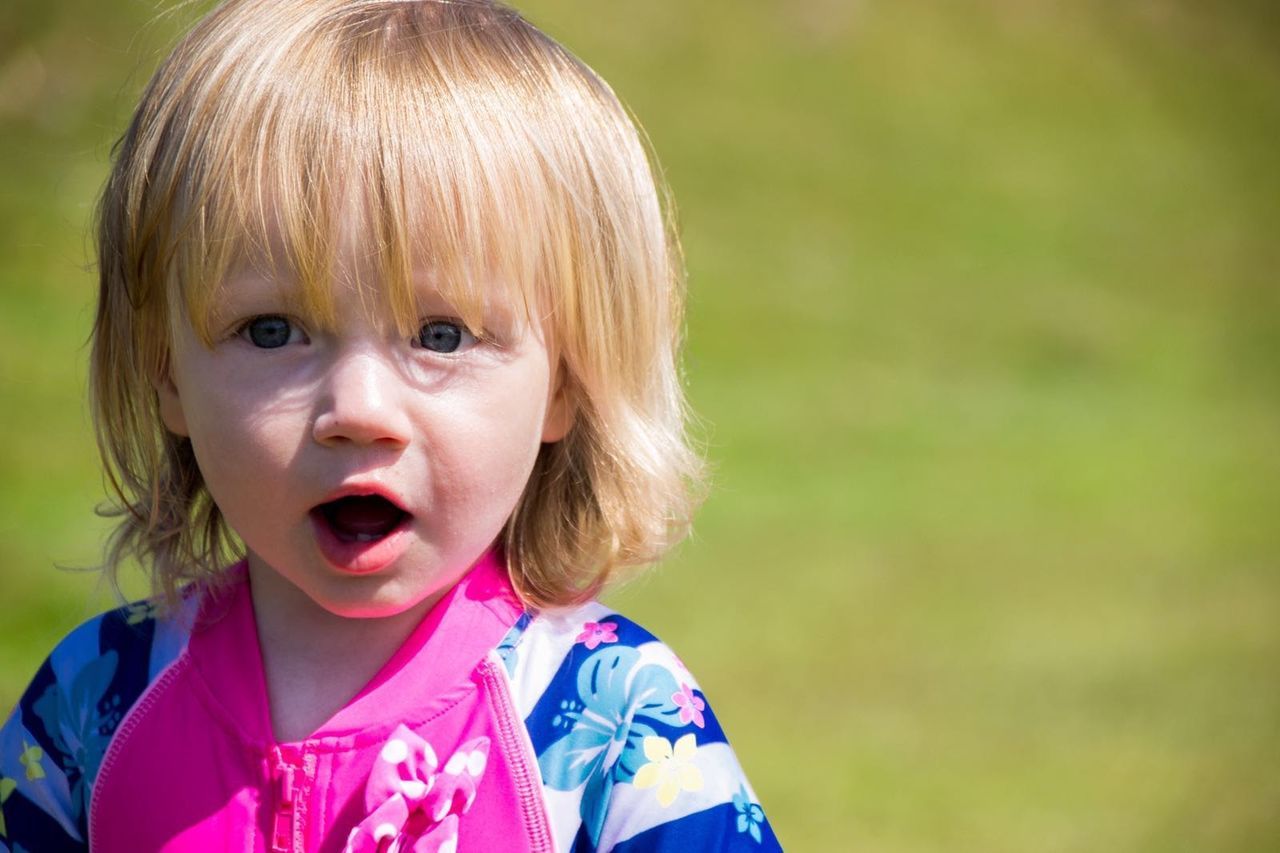 Close-up of cute girl with blond hair in yard