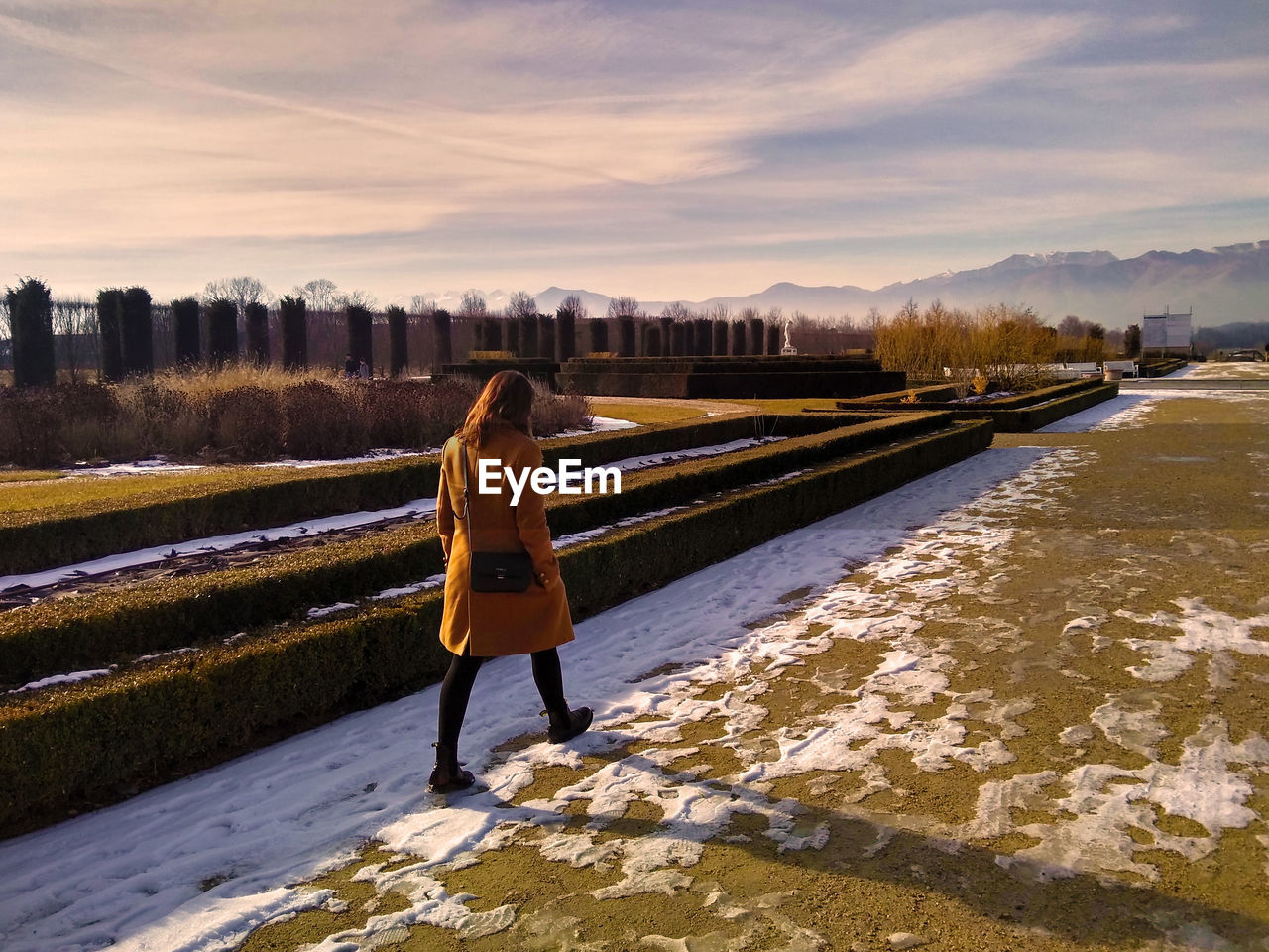 Young woman walking on field against sky during winter