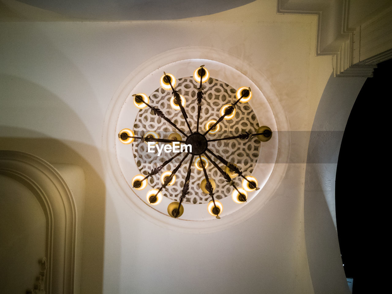 LOW ANGLE VIEW OF ILLUMINATED CHANDELIER HANGING ON CEILING IN BUILDING