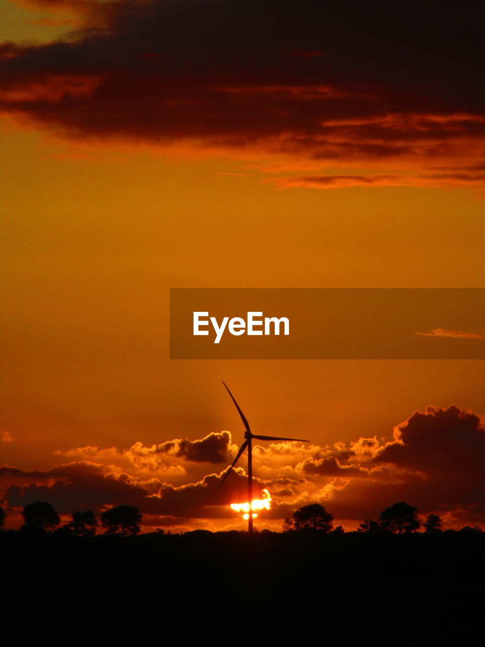 SILHOUETTE OF WIND TURBINES AGAINST DRAMATIC SKY