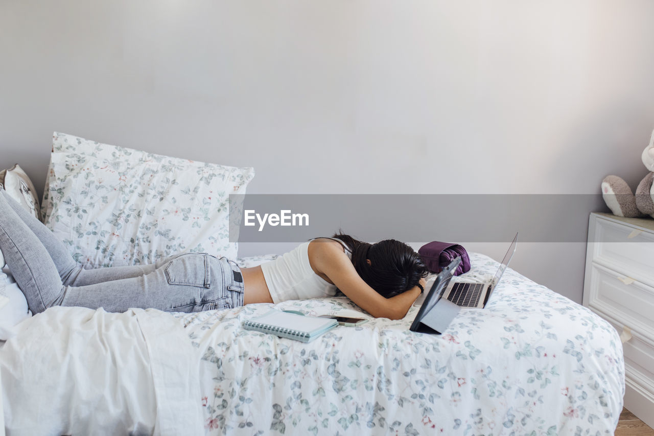 Girl taking nap with wireless technologies on bed at home