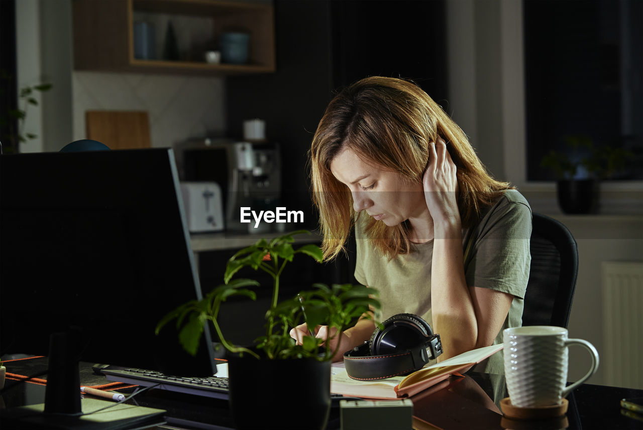 Woman works at home office remotely, using computer