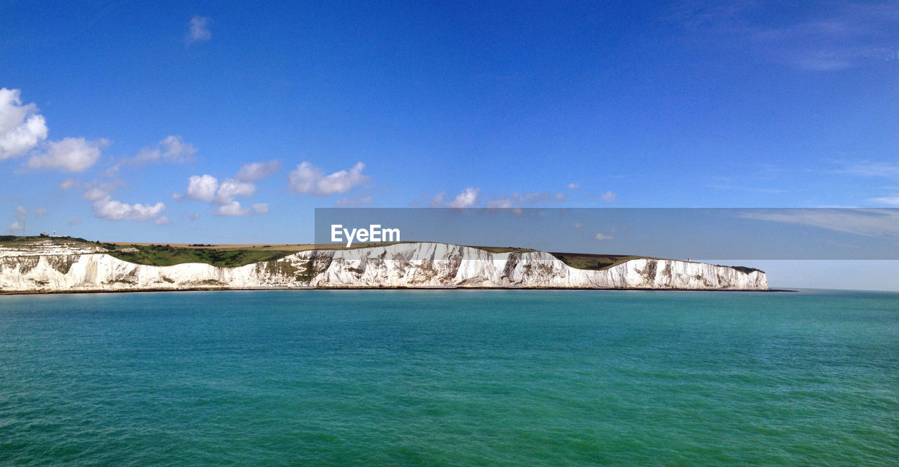 Sea and white cliffs of dover against blue sky