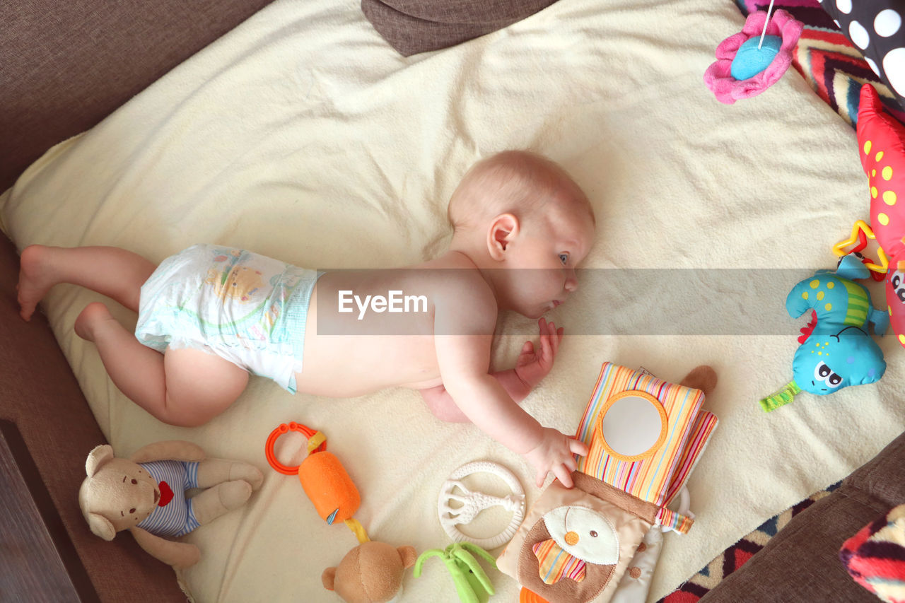 HIGH ANGLE VIEW OF BABY LYING ON BED