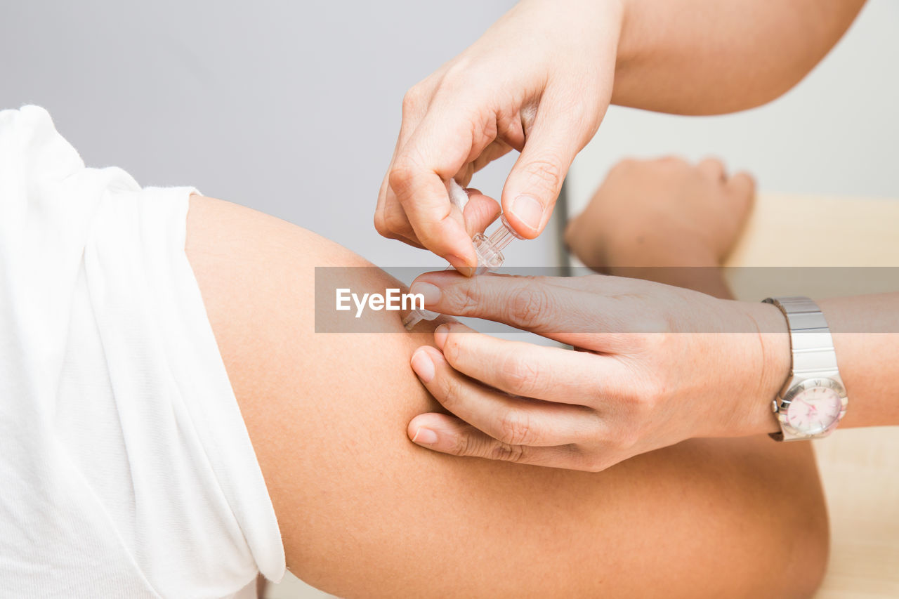 Cropped hand of female doctor vaccinating male patient in clinic