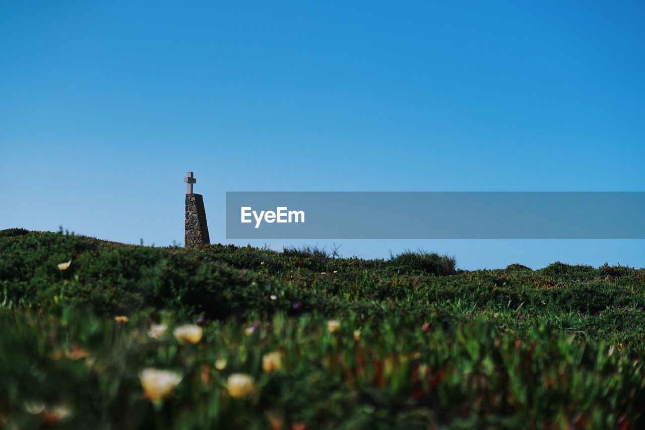 LIGHTHOUSE AMIDST FIELD AGAINST CLEAR SKY