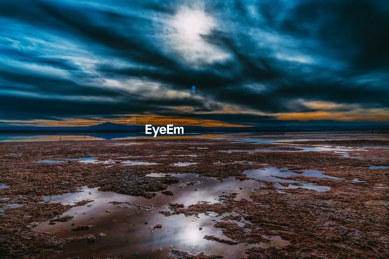 Scenic view of snowcapped field against dramatic sky during sunset