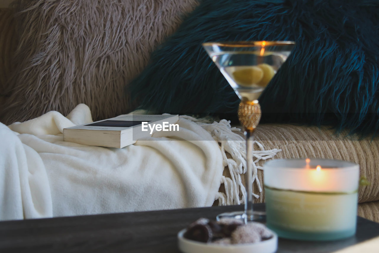 CLOSE-UP OF WINE GLASSES ON TABLE WITH ILLUMINATED CANDLES