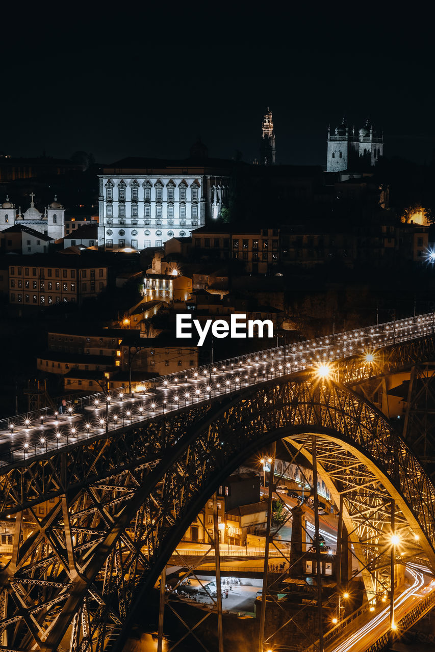 Illuminated bridge over river in city at night