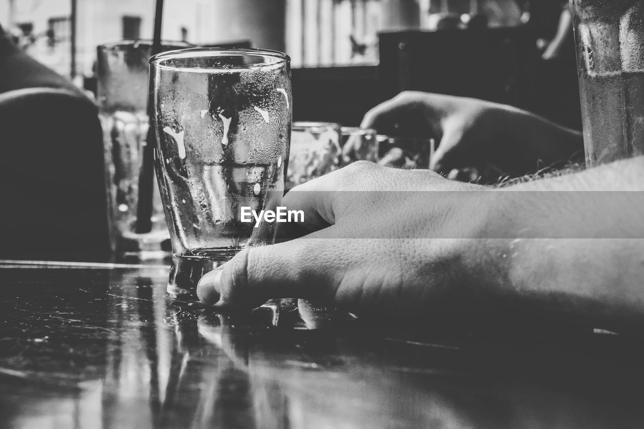 Close-up of cropped man hand holding empty glass on table