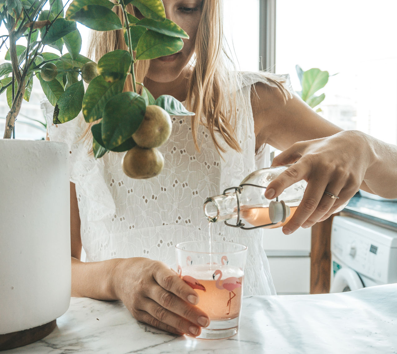 Woman pouring drink on table at home