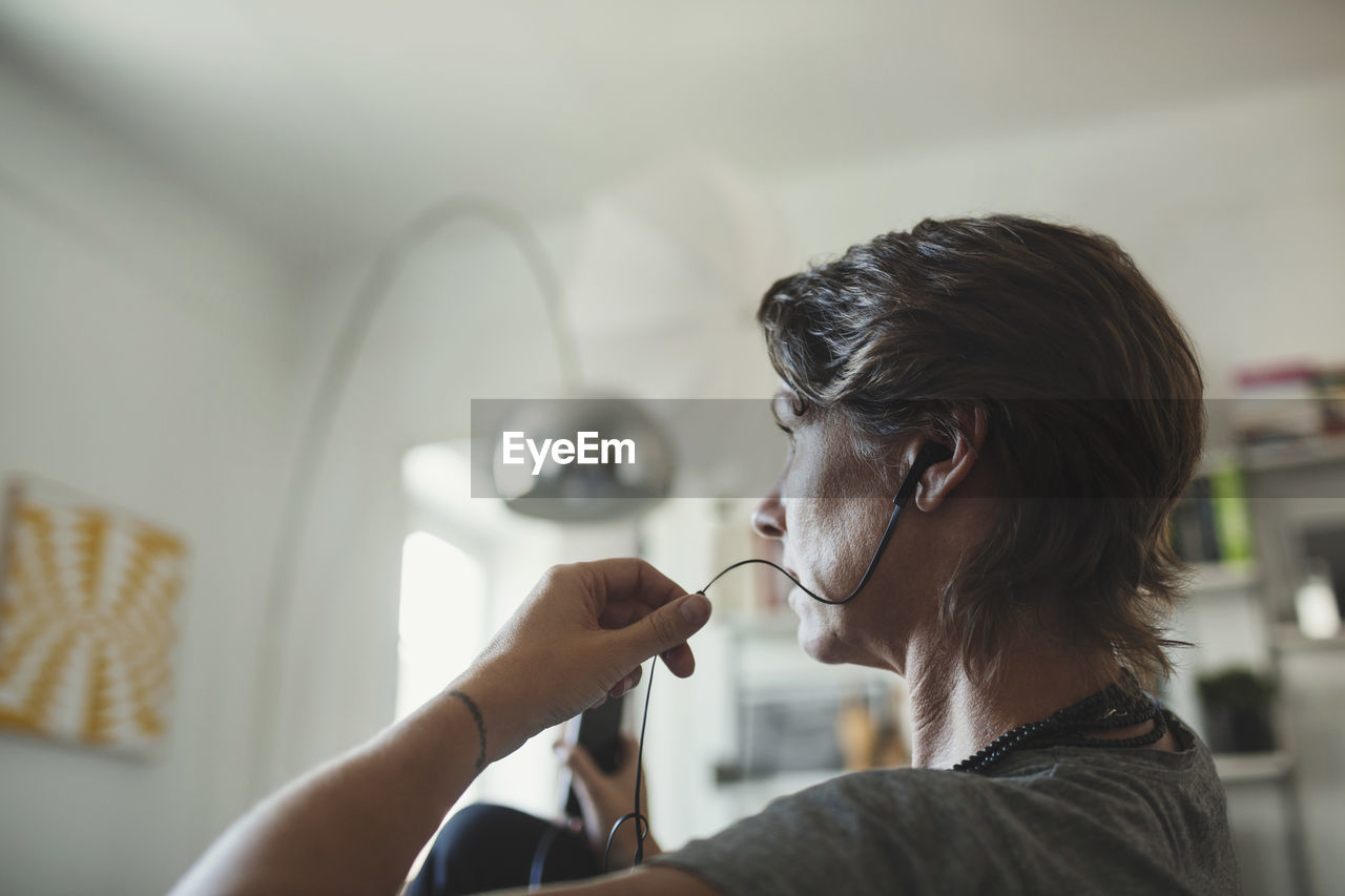 Side view of architect talking through in-ear headphones at home