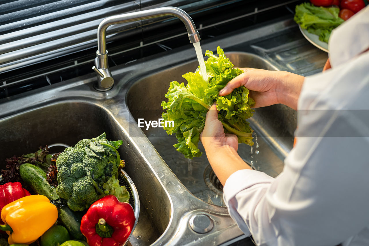 MIDSECTION OF PERSON PREPARING VEGETABLES AT HOME