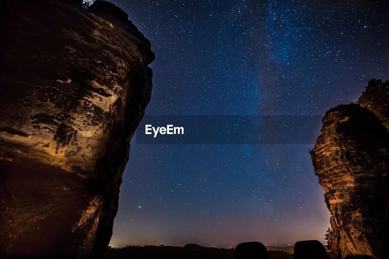 Low angle view of rock formations against star field at night