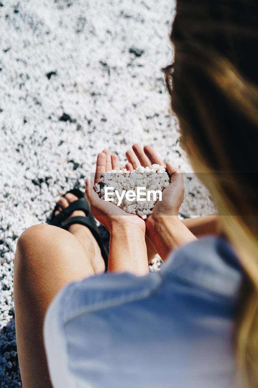 HIGH ANGLE VIEW OF WOMAN HAND ON ROCKS