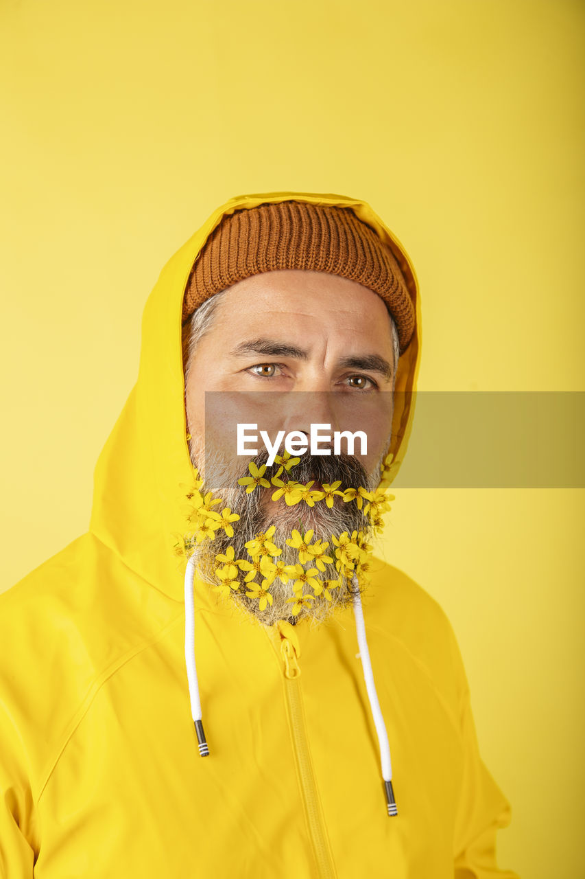 Handsome man with flower beard on yellow background person