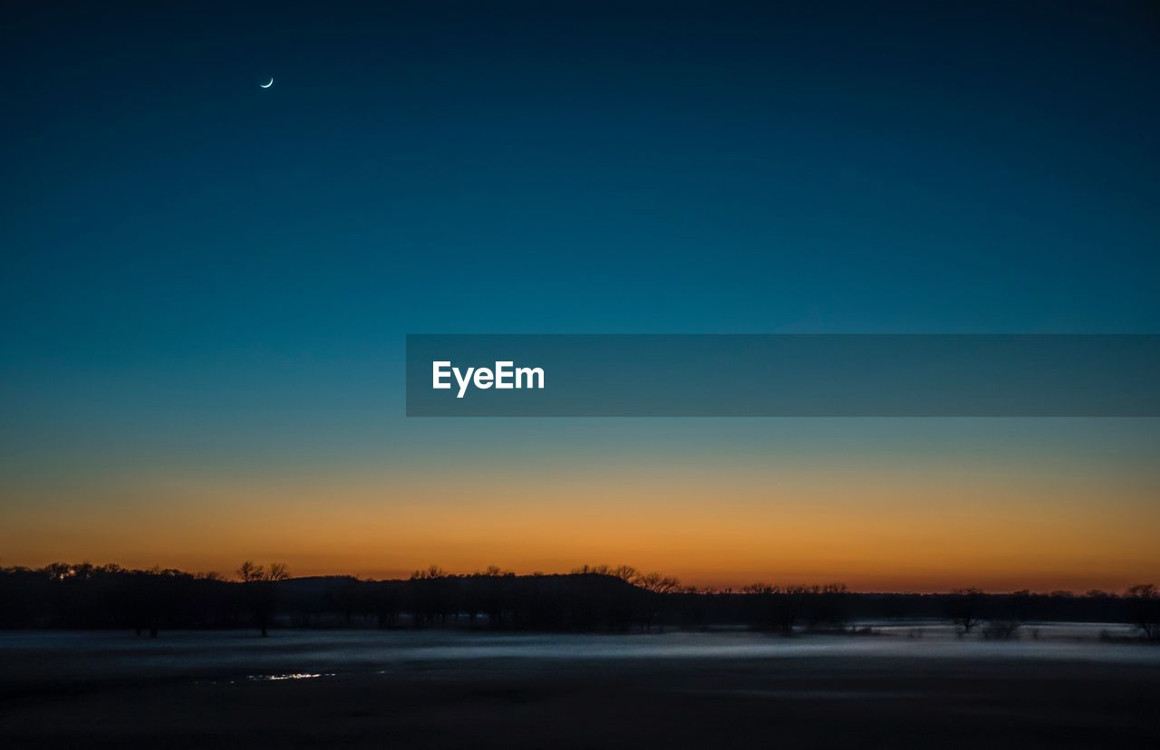 Scenic view of river against clear sky at sunset