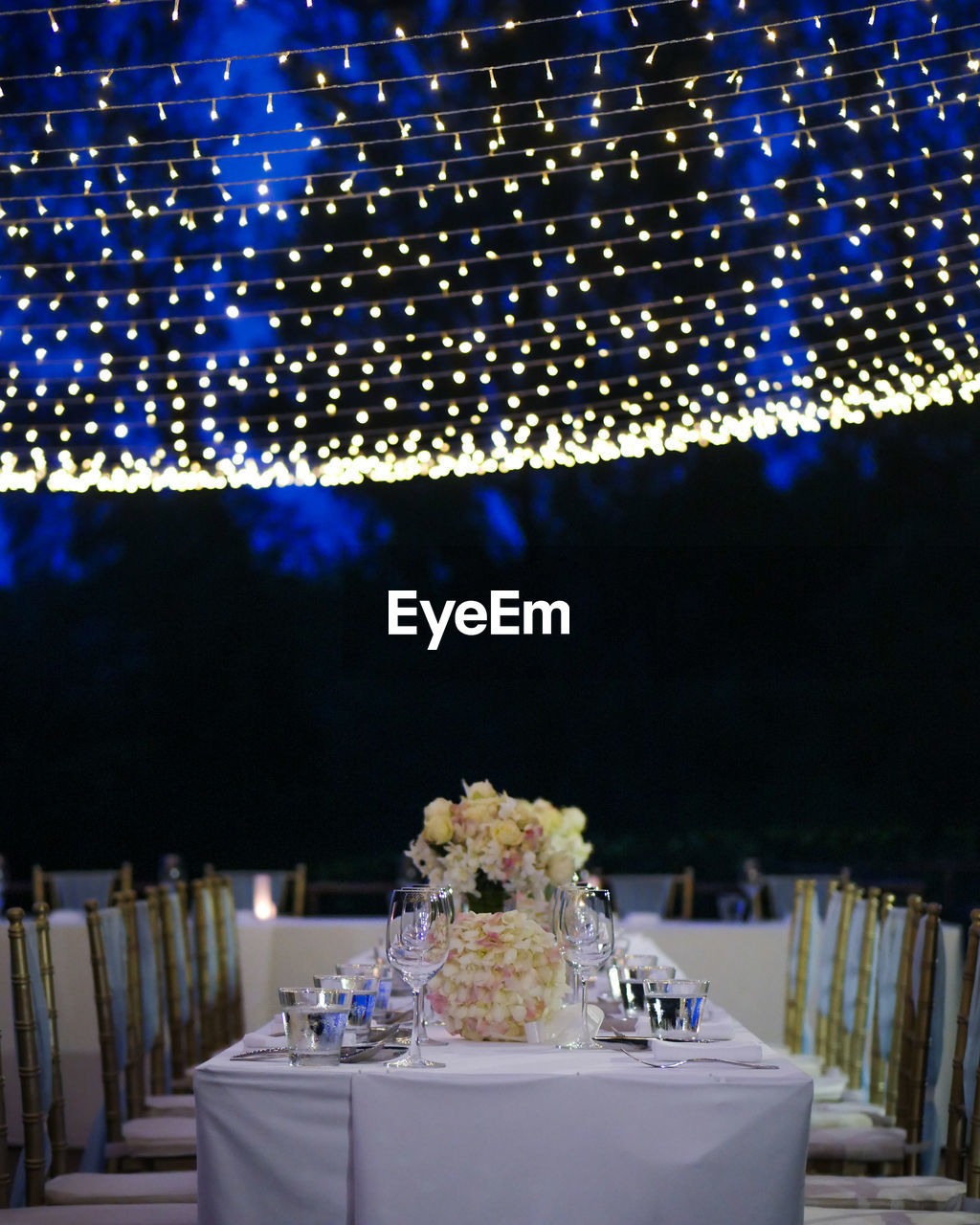 Lighting over empty dining table at dusk during wedding reception