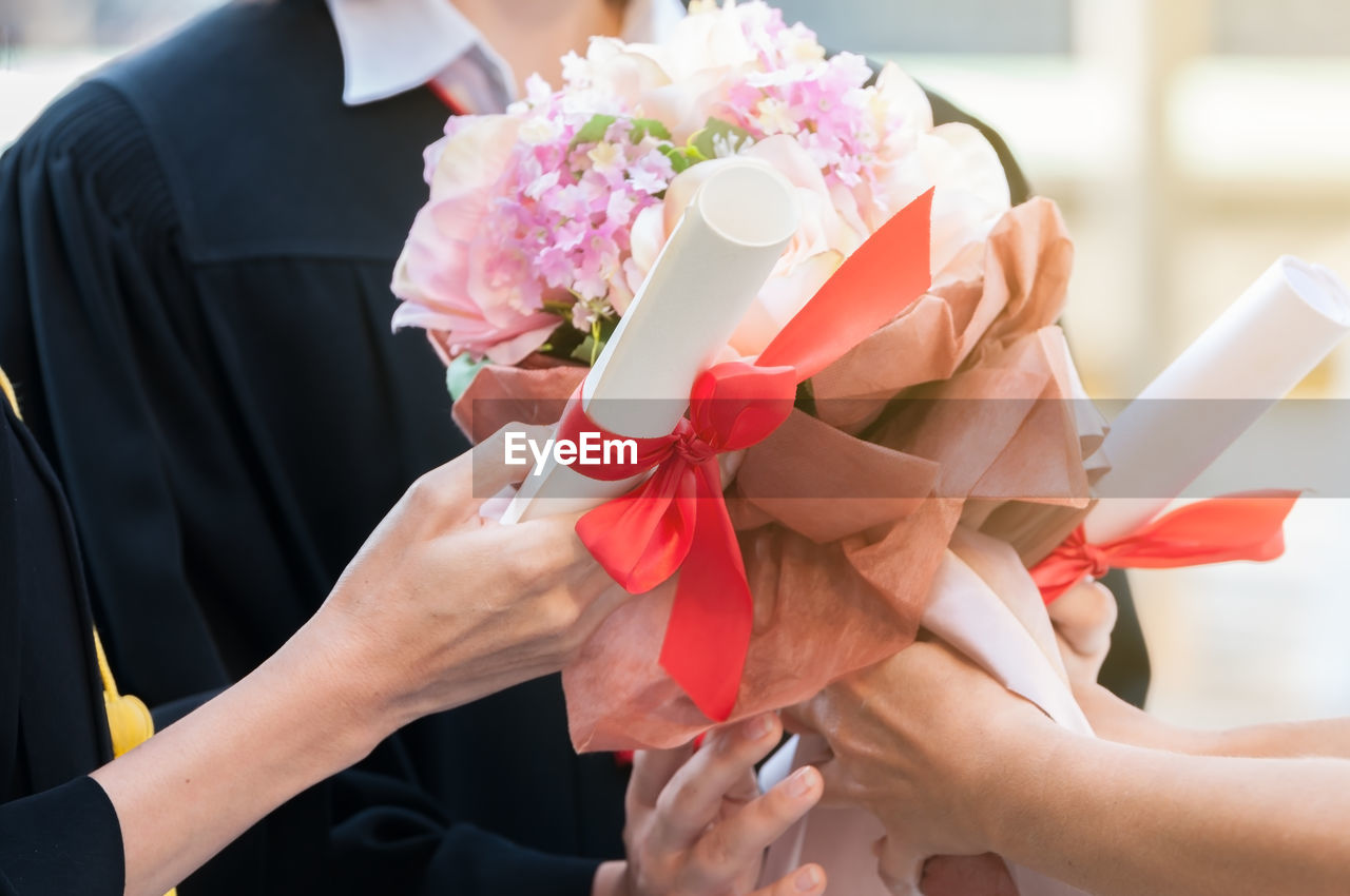 MIDSECTION OF WOMAN HOLDING BOUQUET OF RED ROSE FLOWER