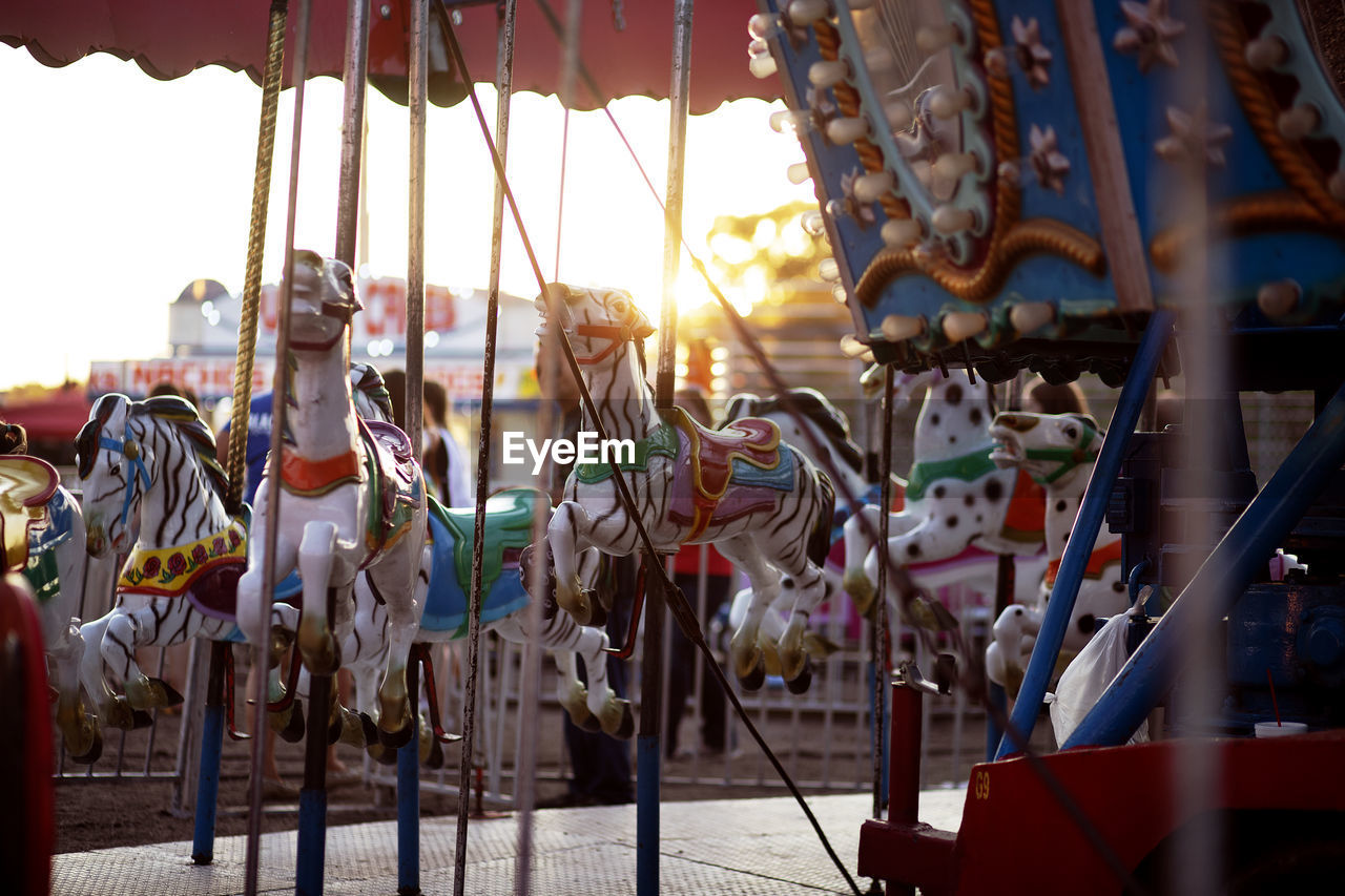 Carousel hanging in amusement park against sky