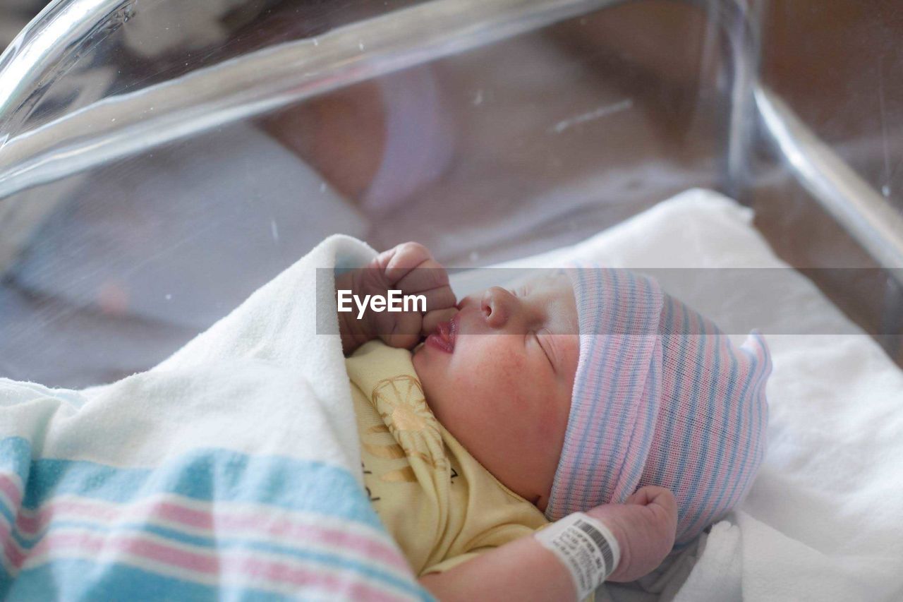 High angle view of baby girl sleeping in glass container at hospital