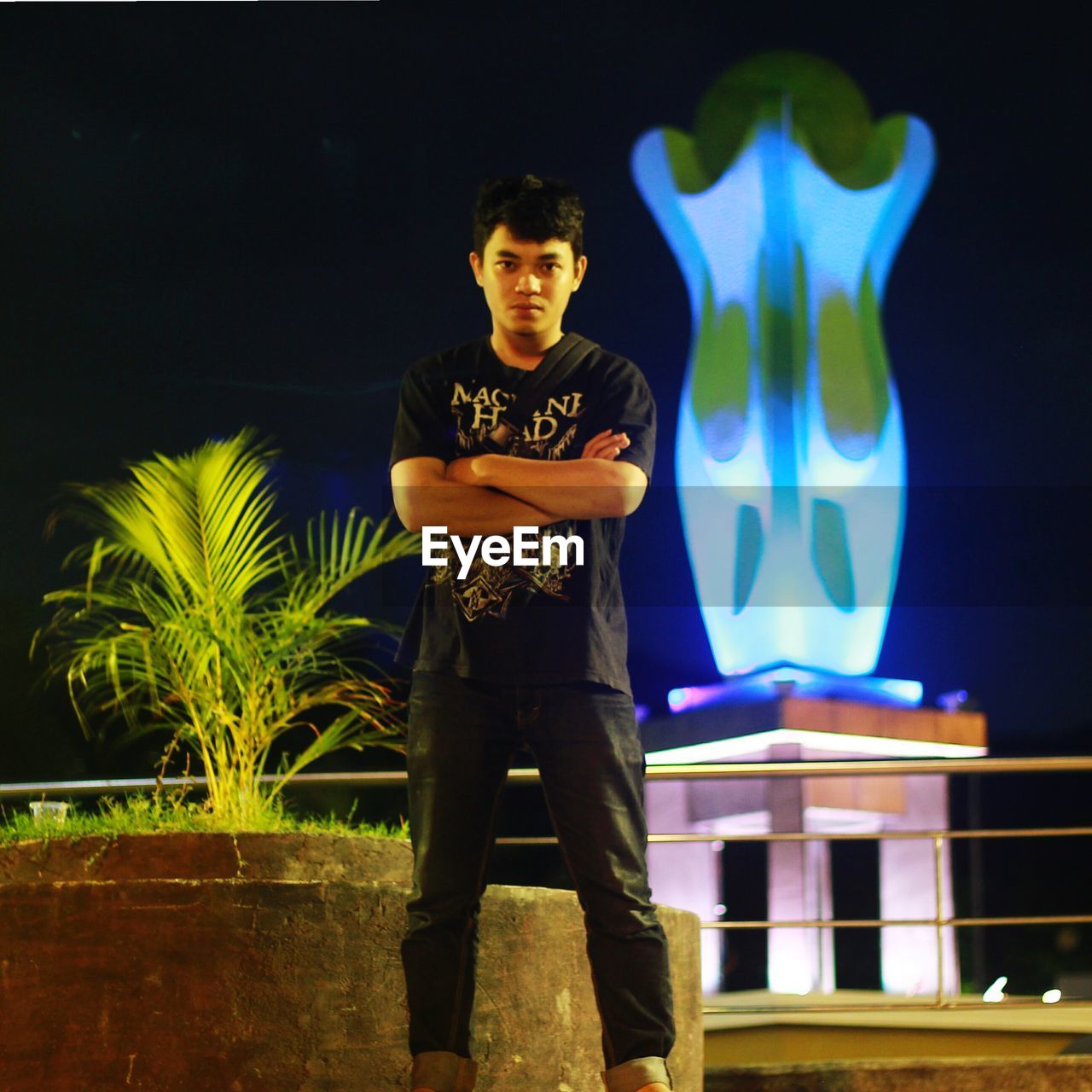 Portrait of young man standing against illuminated wall