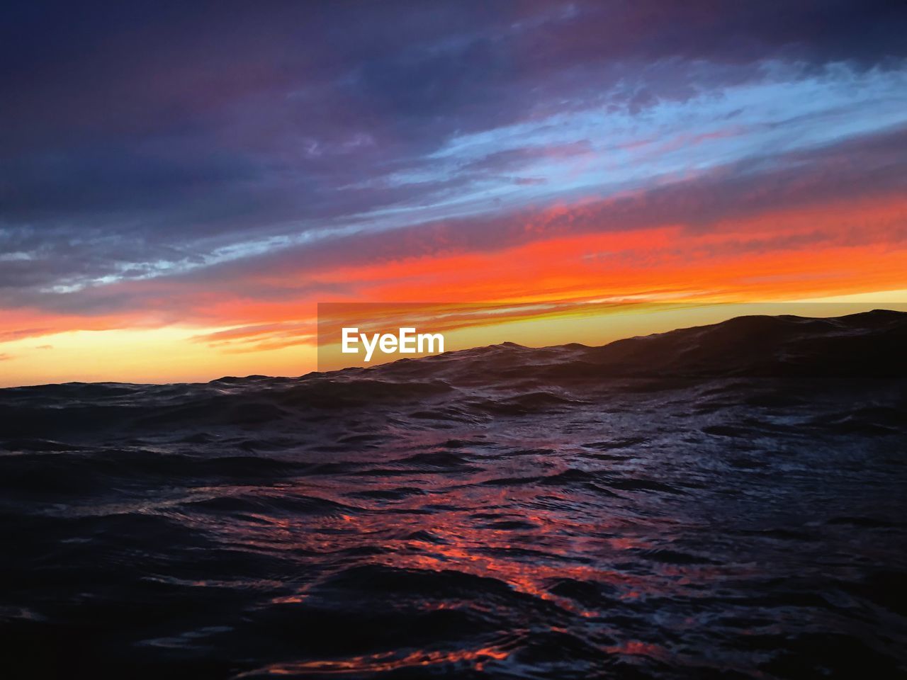 Scenic view of sea against dramatic sky during sunset