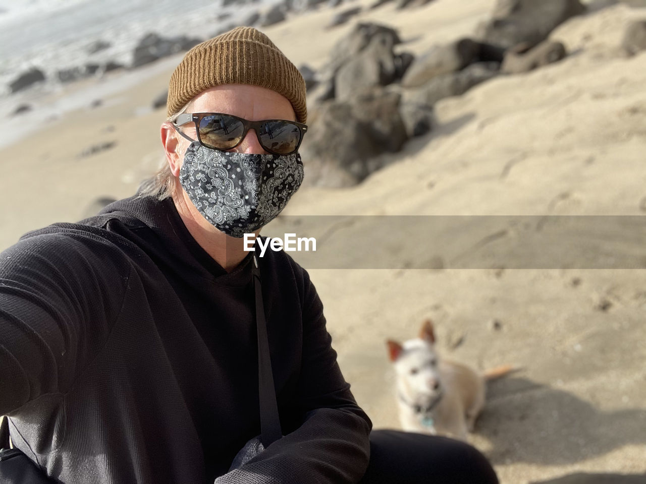 Portrait of man wearing sunglasses on beach with his dog