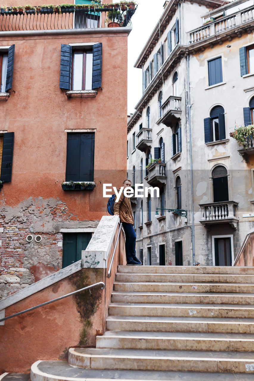 Young blond guy in a brown jacket in middle of streets of venice