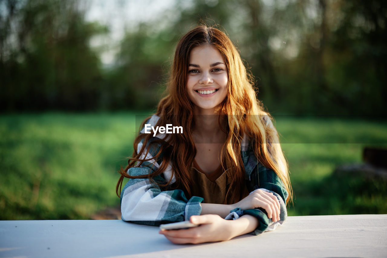 portrait of young woman using mobile phone while sitting outdoors