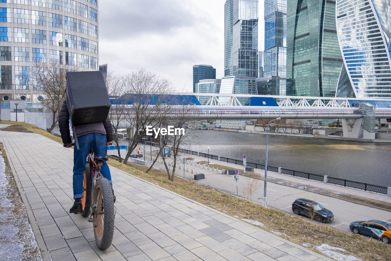 Food delivery service company by courier on bicycle near business center moscow city, moscow, russia