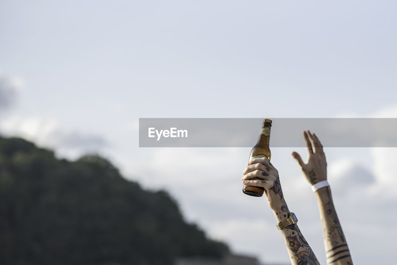 Cropped tattooed hand holding beer bottle