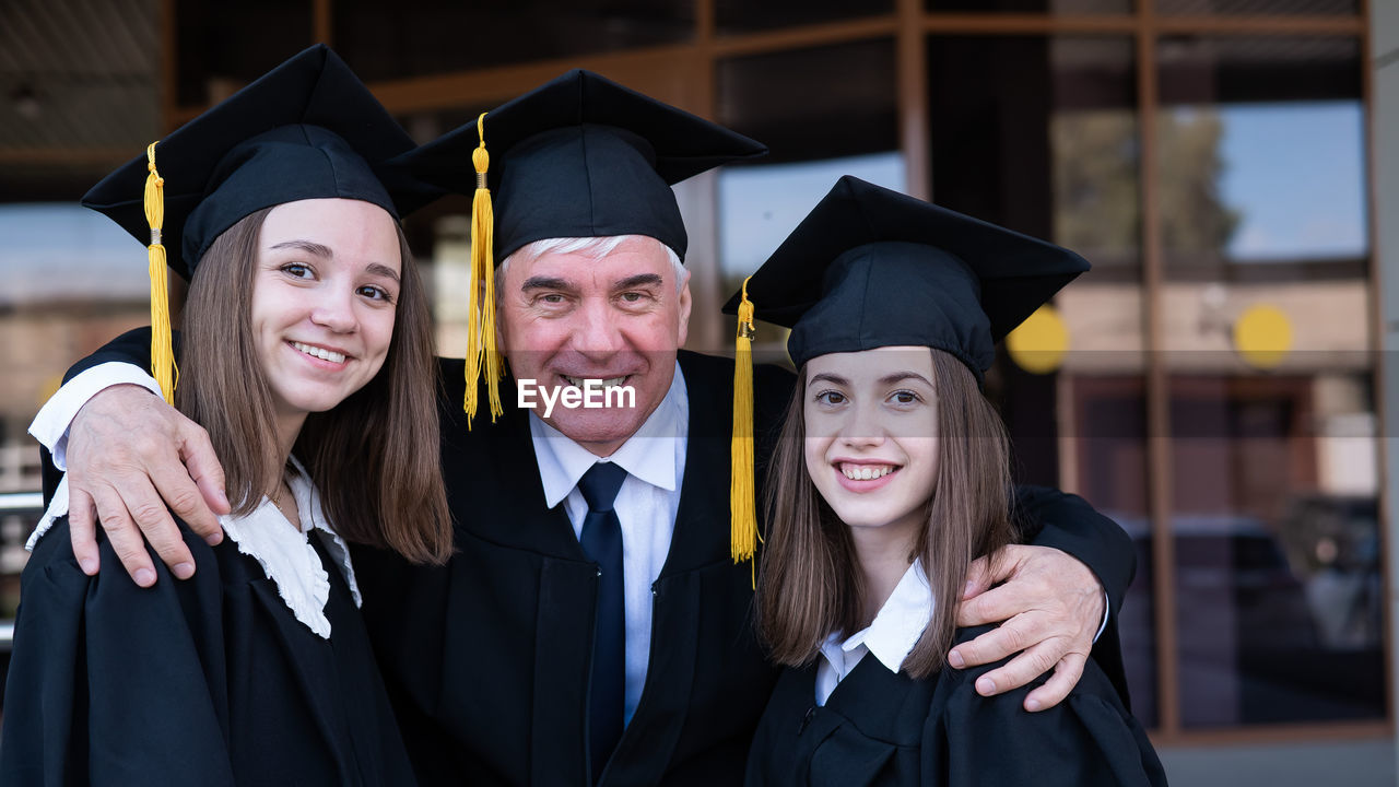 portrait of smiling woman wearing graduation gown standing outdoors