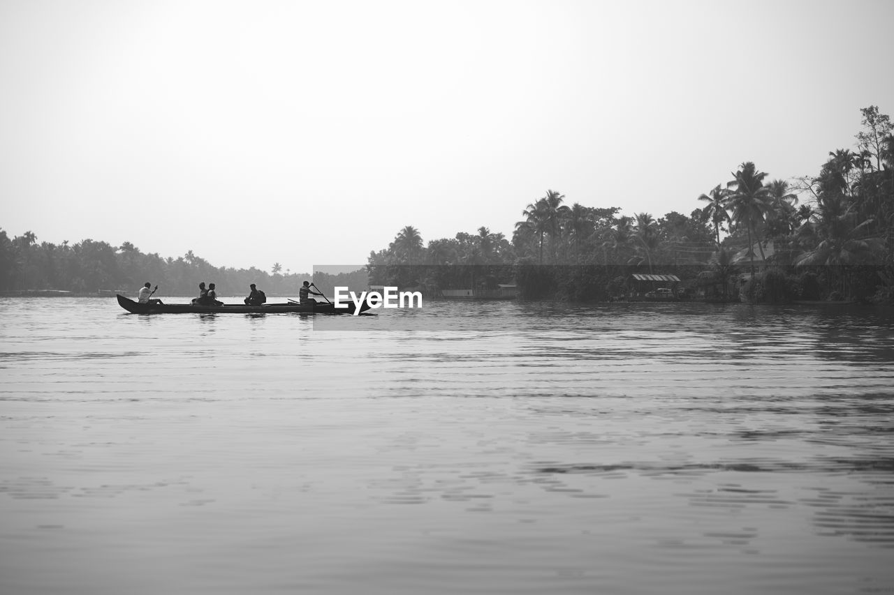 PEOPLE IN LAKE AGAINST CLEAR SKY