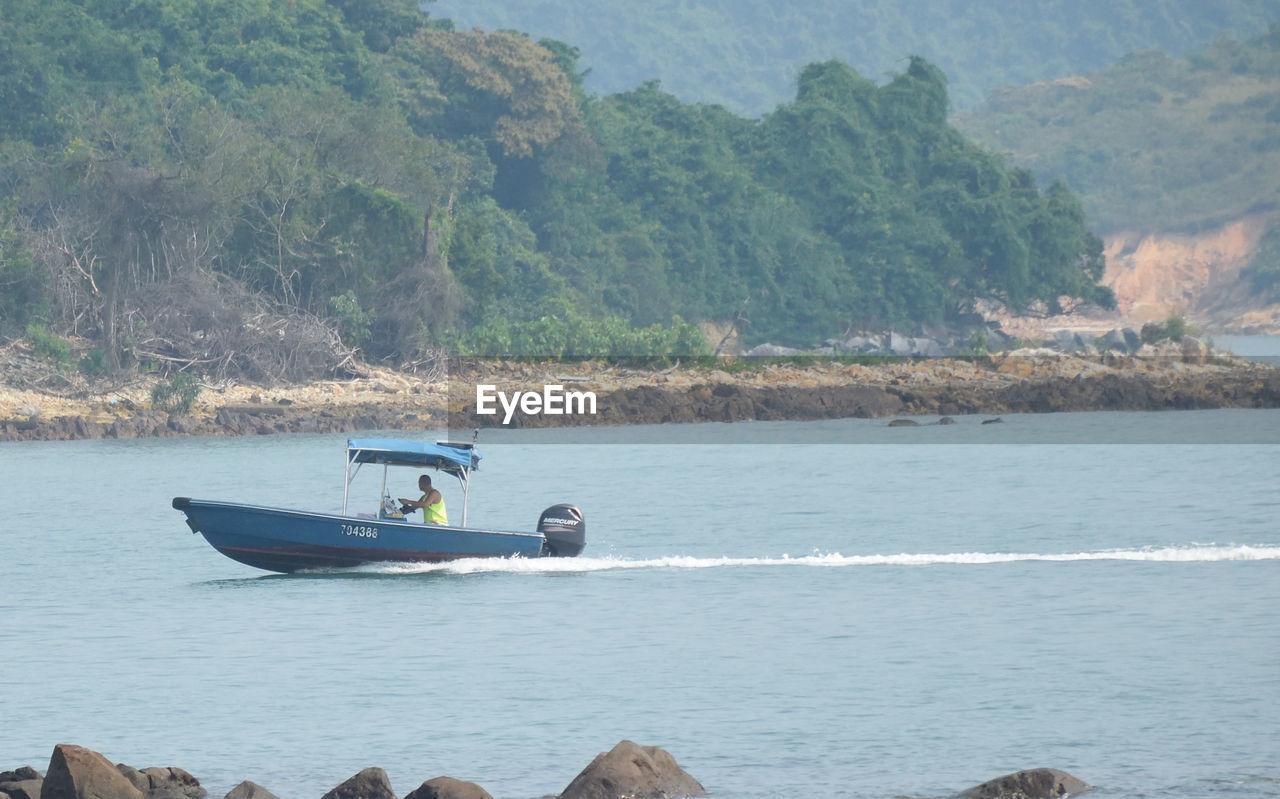 BOAT IN SEA BY MOUNTAINS