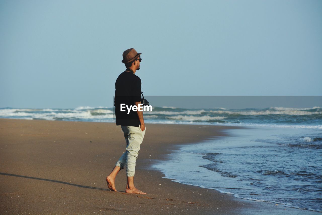 Full length of man standing at beach against clear sky