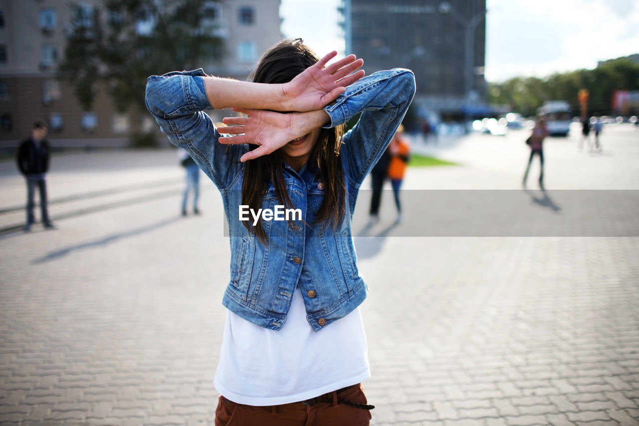 Woman covering face while standing on townsqaure