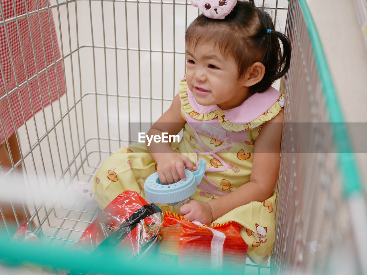 High angle view of cute girl sitting in shopping cart