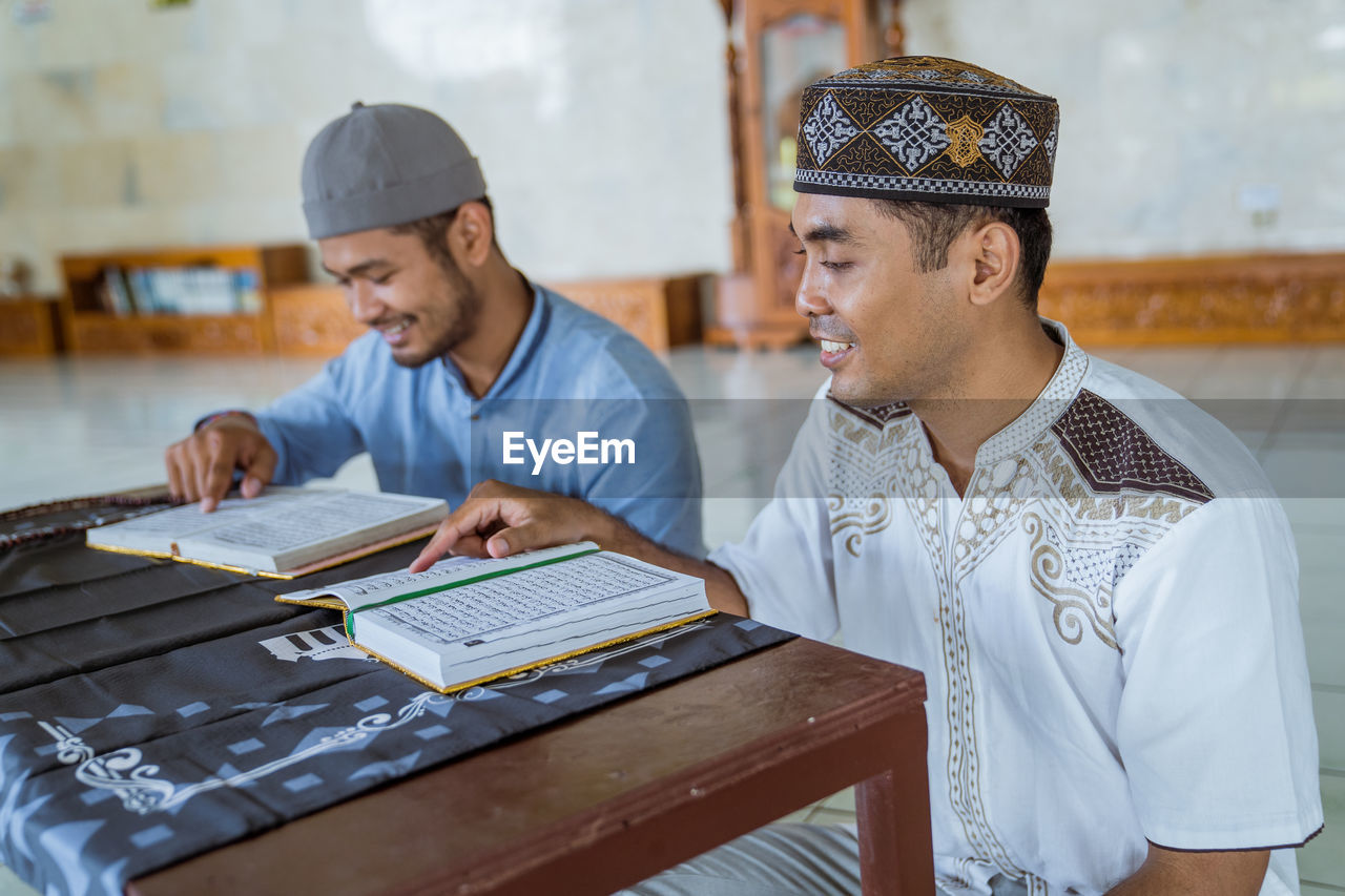 Smiling men reading koran at mosque