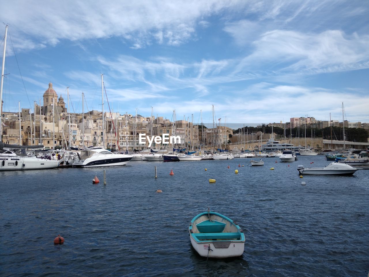 SAILBOATS MOORED ON SEA BY CITY AGAINST SKY